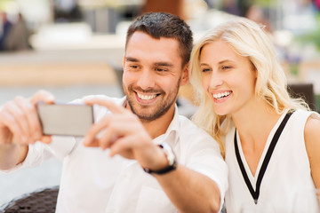happy couple taking selfie with smartphone at cafe