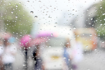 A very rare rainy day in Bangkok, Thailand with van and people as seen through car windows with rain drops visible on the window.