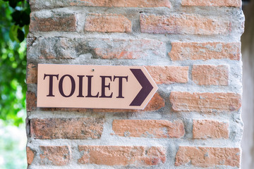 Fototapeta na wymiar Guide post arrow to toilet on brick column
