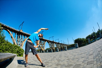 man runner athlete warming up before jogging along a city bay and railroad bridge at the early morning. man fitness sunset jogging workout wellness concept.
