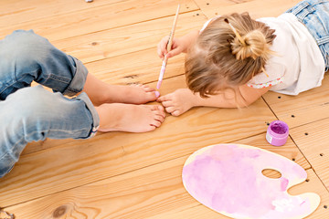 Sisters play and indulge, do manicure with brushes and paints to paint