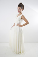 Fototapeta na wymiar Studio Shot Of Sensual Elegant Woman With Classic Hairstyle Posing In Beautiful White Dress Against White Background