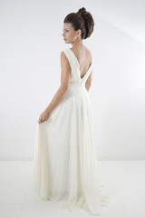 Fototapeta na wymiar Studio Shot Of Sensual Elegant Woman With Classic Hairstyle Posing In Beautiful White Dress Against White Background