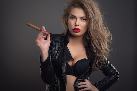 young woman with sigar on dark background studio shot