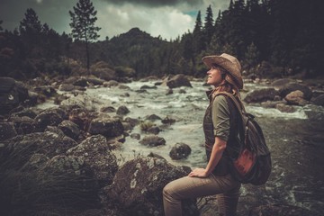 Naklejka premium Beautiful woman hiker enjoying amazing landscapes near wild mountain river.