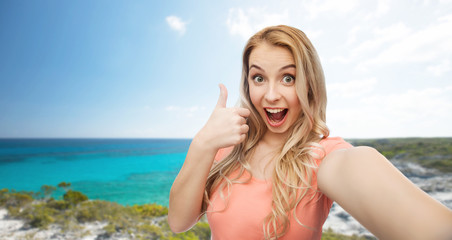 Naklejka premium happy woman taking selfie and showing thumbs up