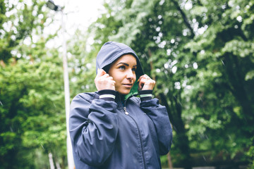 Running in city park. Attractive young woman runner outside jogging on cold rainy day. Rain drops visible.