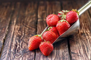 strawberries with kitchen scoop on wooden