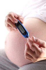 Kobieta w ciąży trzyma glukometr 