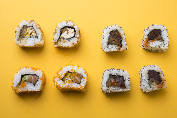 Various kinds of sushi food served on yellow blackground