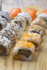 Different Sushi rolls,wasabi and ginger on a plate on wooden bac