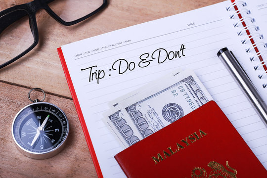 Tripl : Do & Don’t text message on note book with passport, glasses, hundred dollar bills, compass and pen on wooden table. - Powered by Adobe