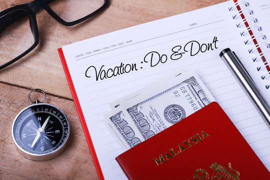 Vacation : Do & Don’t text message on note book with passport, glasses, hundred dollar bills, compass and pen on wooden table. - Powered by Adobe
