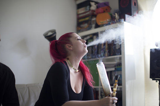 Young Woman Smoking Drugs In Bong At Home