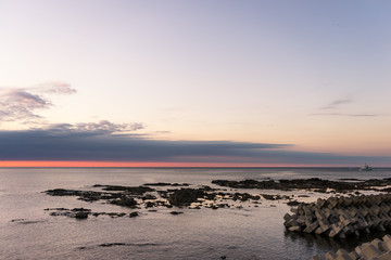 Fototapeta na wymiar rock beach near tranquil sea at sunrise