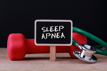 Medical concept - Stethoscope and dumbbell on wood with Sleep Apnea word