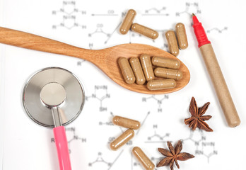 Capsules of herbs on spoon and stethoscope