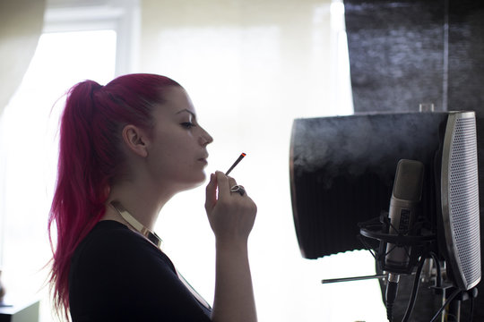Young Woman Smoking Joint At Home And Recording Music