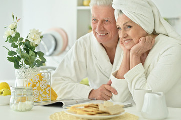 Obraz na płótnie Canvas mature couple in a bathrobe at kitchen
