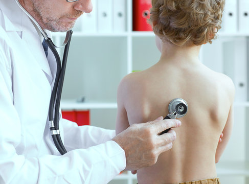 Doctor examining a child patient teeth by  orthodontic tools.