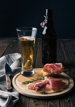 Spanish tapas with jamon, glass and bottle of beer on a wooden background
