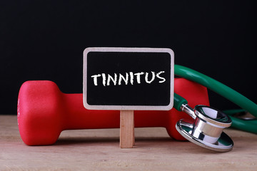 Medical concept - Stethoscope and dumbbell on wood with Tinnitus word