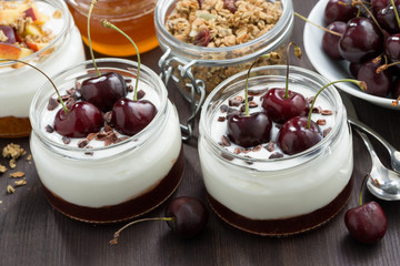 dessert with cream and jam in glass jar on dark wooden table