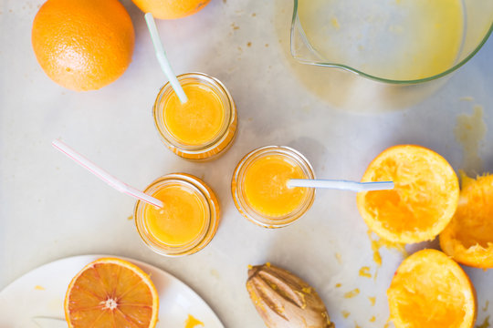 Freshly squeezed orange juice in jars with drinking straws on metallic countertop. Selective focus.