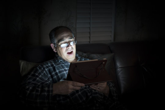 Yawning Man Reading Tablet At Night