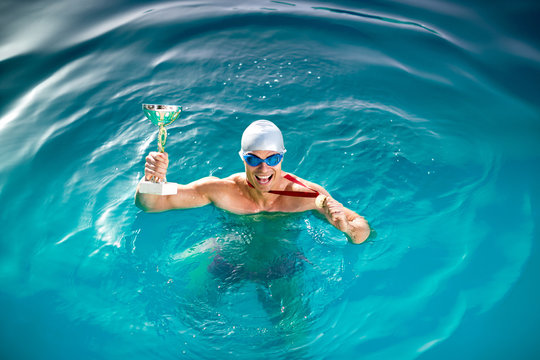 Happy swimmer with goblet and medal