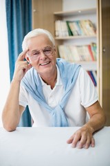 Fototapeta premium Smiling senior man sitting at table