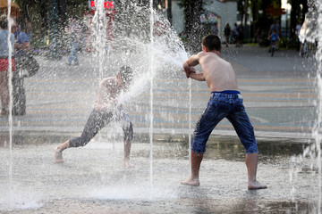 two teenagers playing with water in fountain