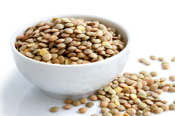 White ceramic bowl of green uncooked lentils isolated on white i