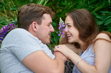 Young happy beautiful couple man and woman lying outdoors on green grass