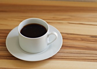 Cup of black coffee on a rustic wooden table. Hot coffee ready for breakfast.