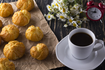Eclair, coffee cup, alarm clock and charmomile.