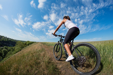 Fototapeta na wymiar Mountain biking happy sportive girl relax in meadows sunny countryside