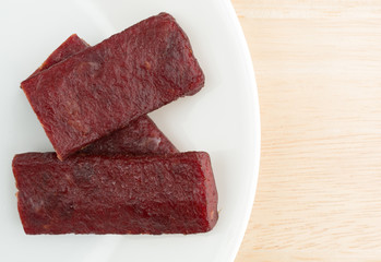 Dried beef steak pieces on a white plate atop a wood table top.