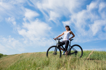 Fototapeta premium Mountain biking happy sportive girl relax in meadows sunny countryside