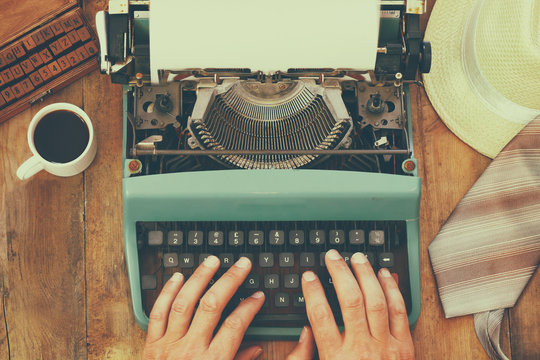 man typing on vintage typewriter with blank page