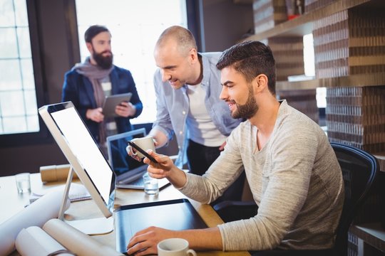 Male creative coworkers discussing over computer