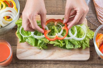 Food series : Making baguette ham sandwich, woman's hands placing bell pepper on baguette sandwich