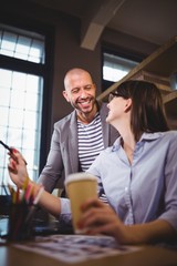 Coworkers smiling while discussing at desk