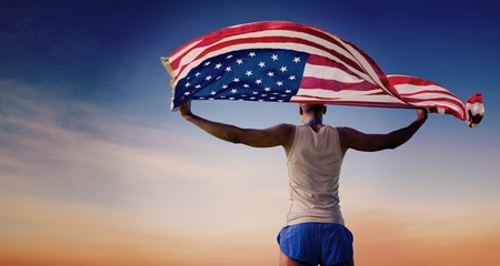 Composite image of rear view of sportsman holding american flag 