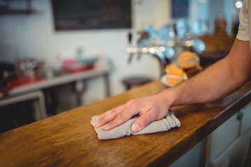 Close-up of waiter cleaning counter at cafe