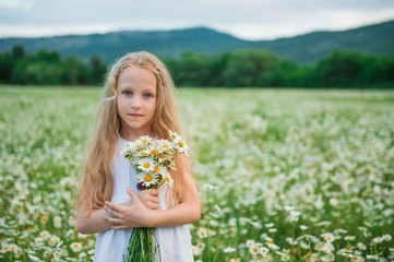 Cute child girl at camomile field