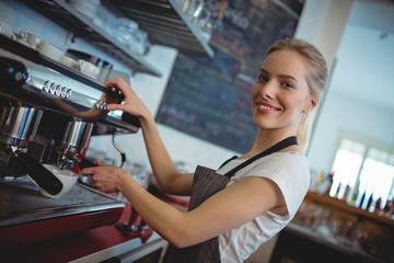 Portrait of happy barista using espresso maker at cafe