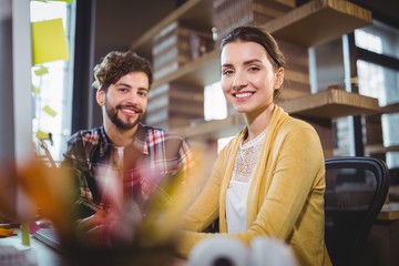 Happy creative business people sitting by desk 