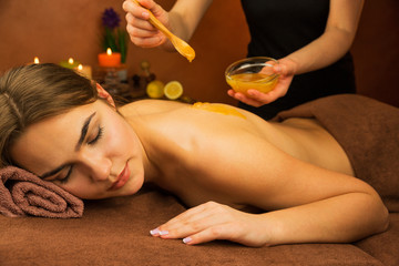 Beautiful woman in spa salon having spa therapy honey procedure - 114057394