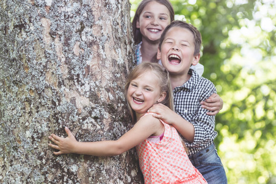 Three Children laughing under big old Tree